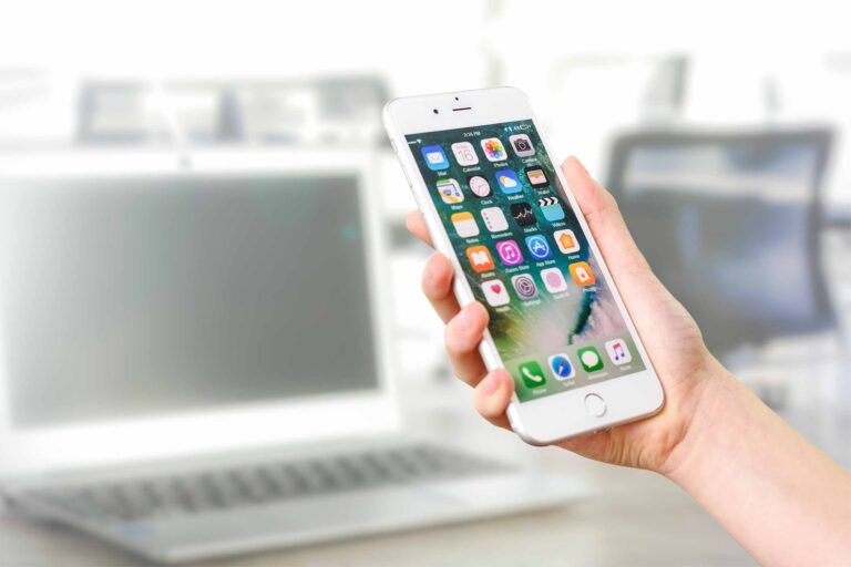 a hand holding an iphone that shows the homescreen