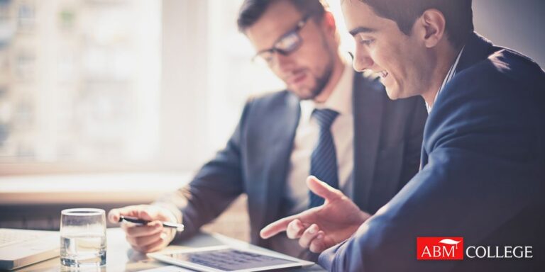 two men in suits discussing about marketing on a tablet