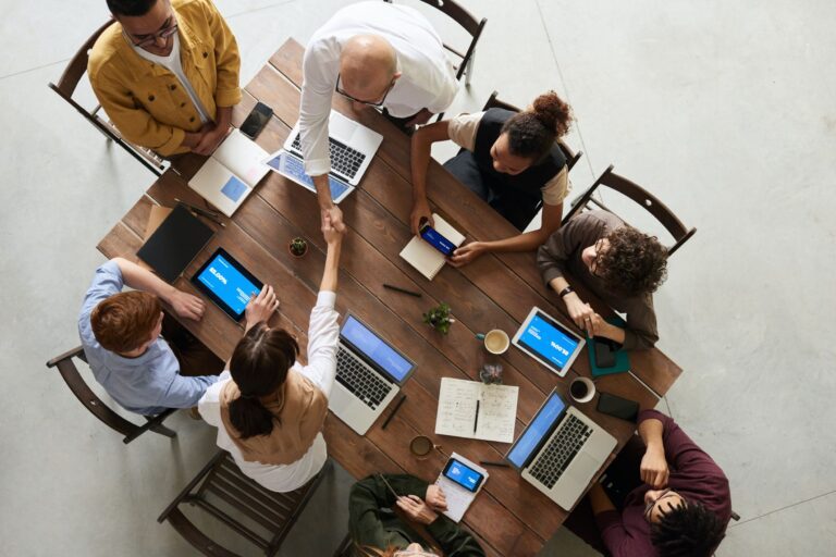 a group of people sitting together on a chair around a table and discussing about business