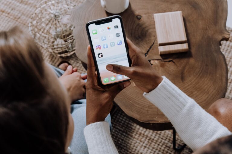 a person holding an iphone and showing the homescreen to another person