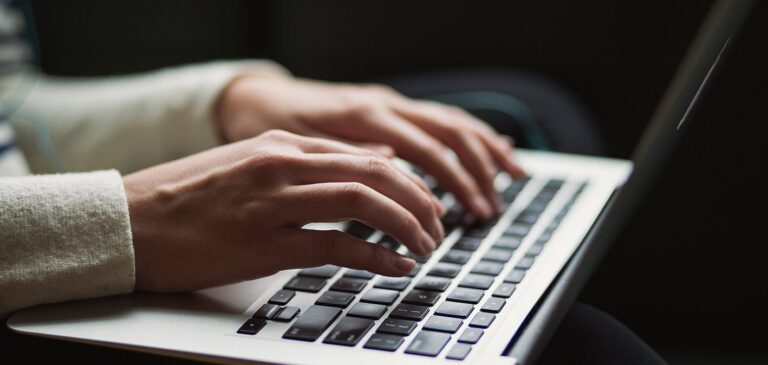 an image showing two hands typing on a laptop