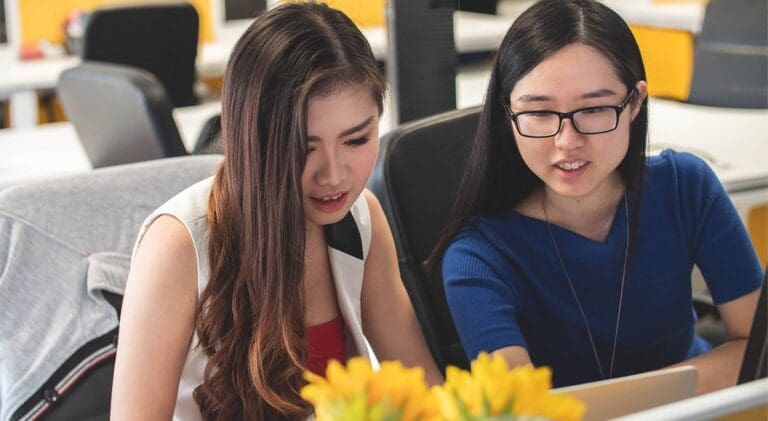 two women working together on their laptop