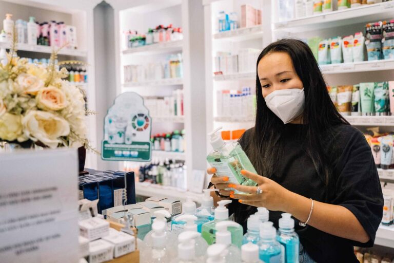a pharmacy assistant checking products while wearing a mask
