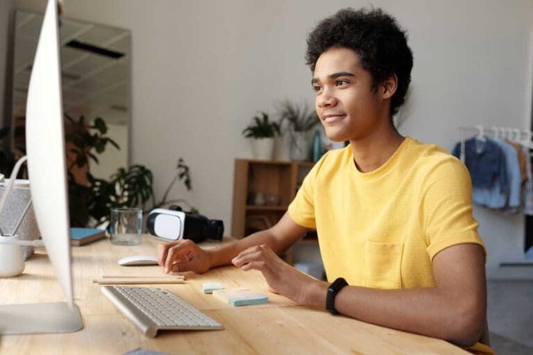 a young man in yellow t-shirt working at his computer