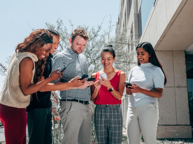 a group of people smiling while looking at their phones