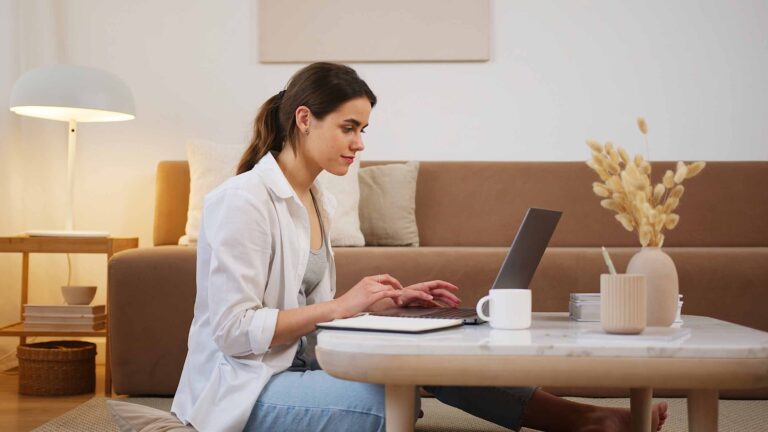 a woman sitting on a coffee table using a laptop