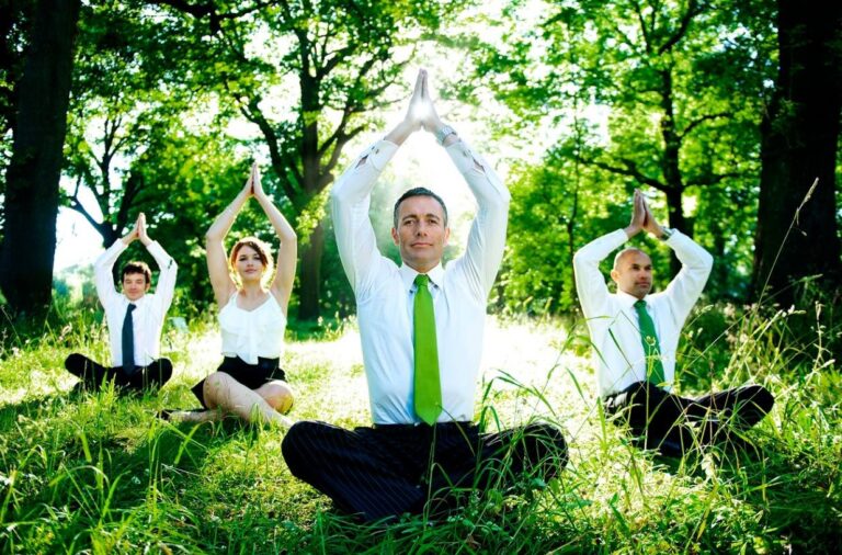 a group of people sitting on the ground with their hands above their head in a pyramid shape with palms attached for meditation