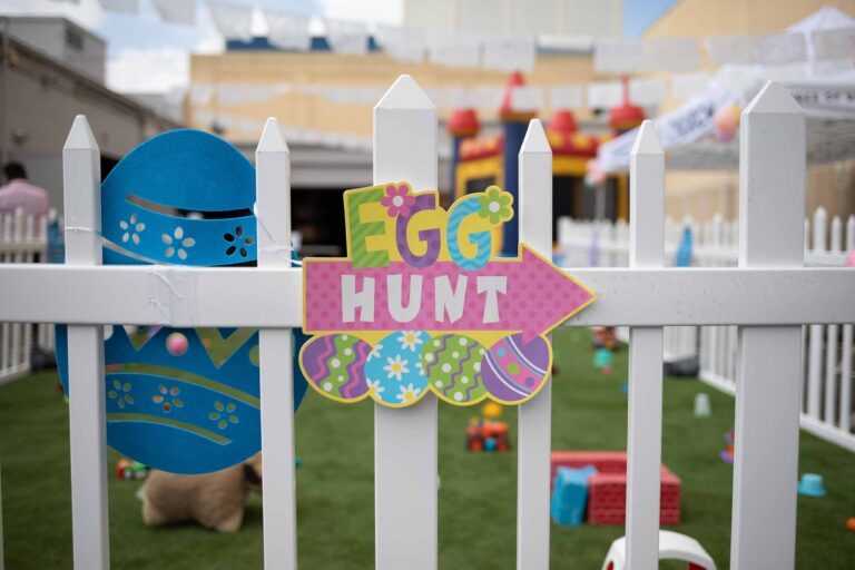 a fence with a sign that has arrow and says "Egg Hunt"