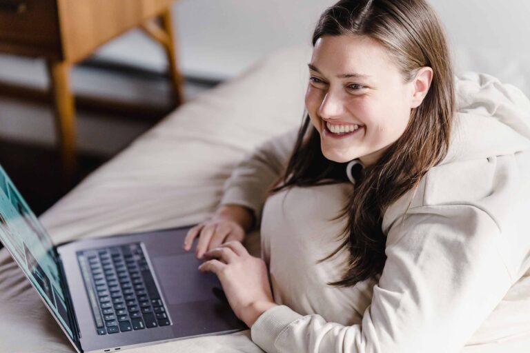 a woman smiling and using her laptop
