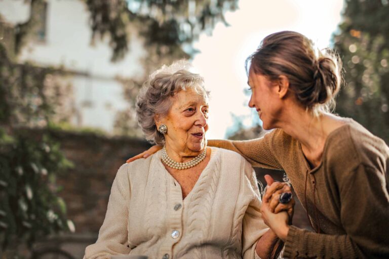 a health care assistant holding hands and talking with a woman