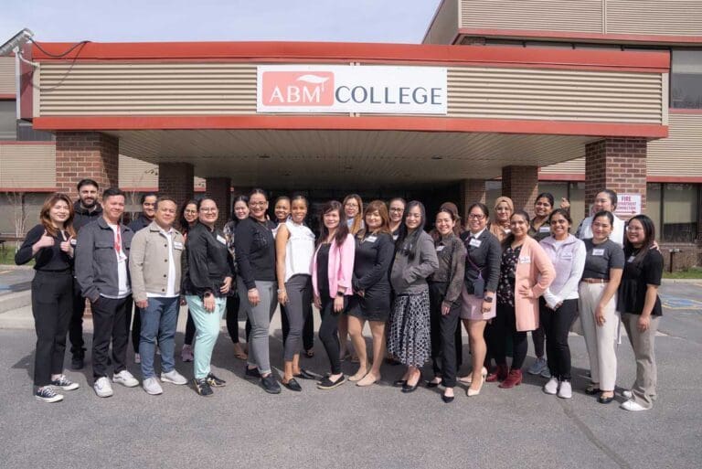 a group of people standing together and posing for a picture in front of ABM College