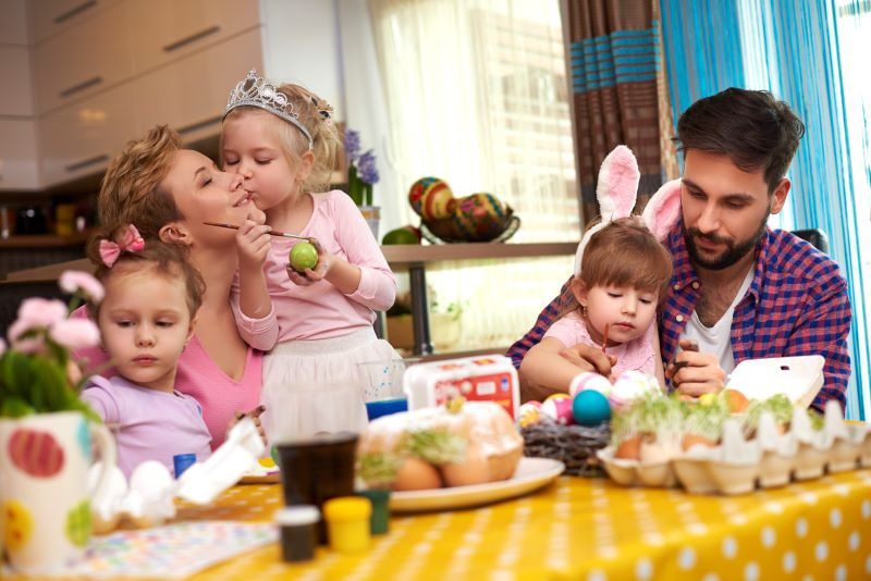 A family with young children decorating Easter Eggs together