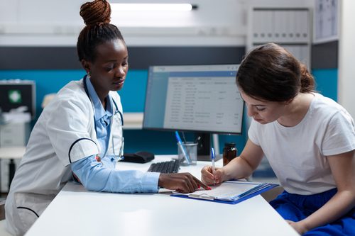 Patient signing papers with Medical office assistant
